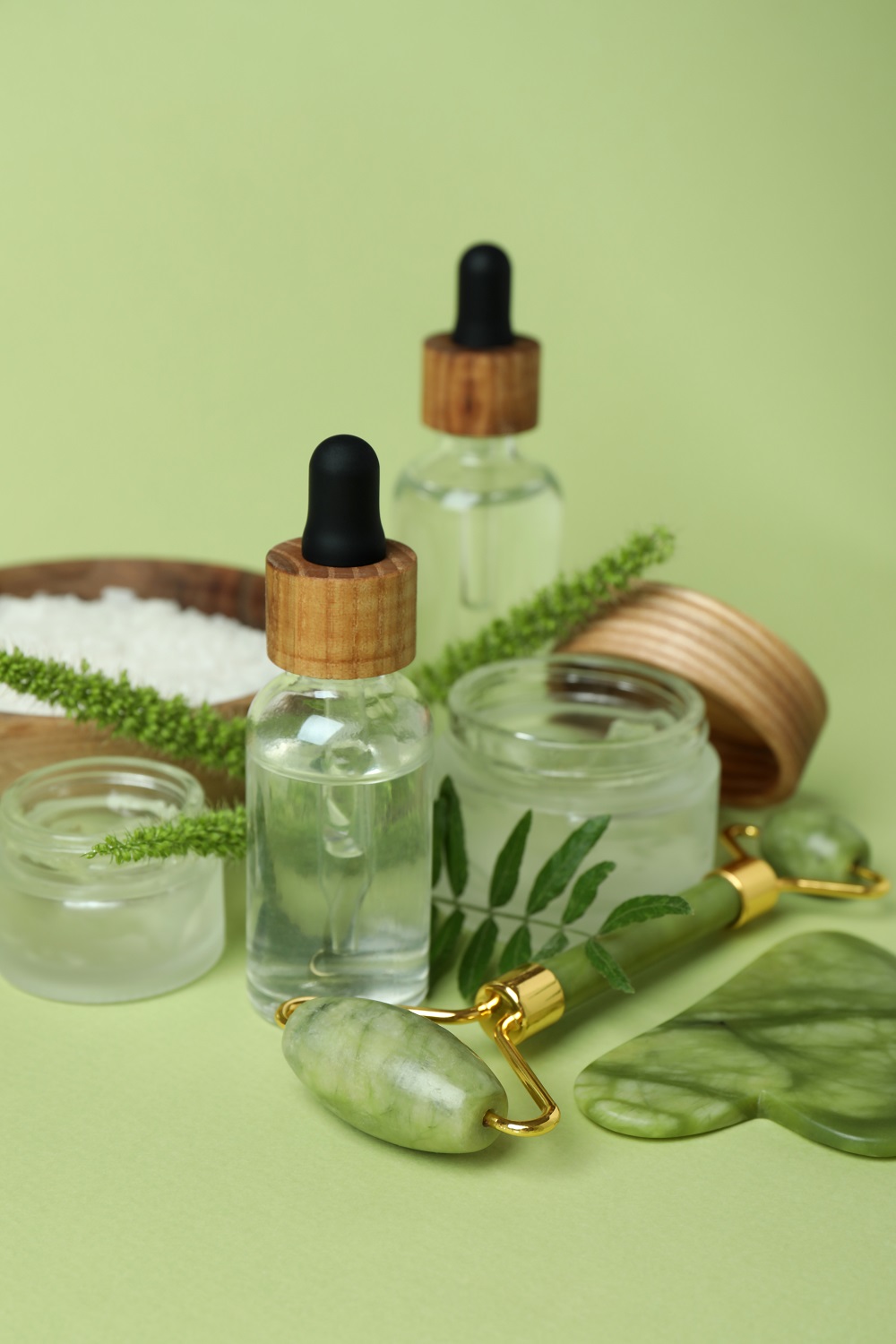 Skin care concept with face roller on green background